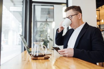 man drinking coffee in front of laptop